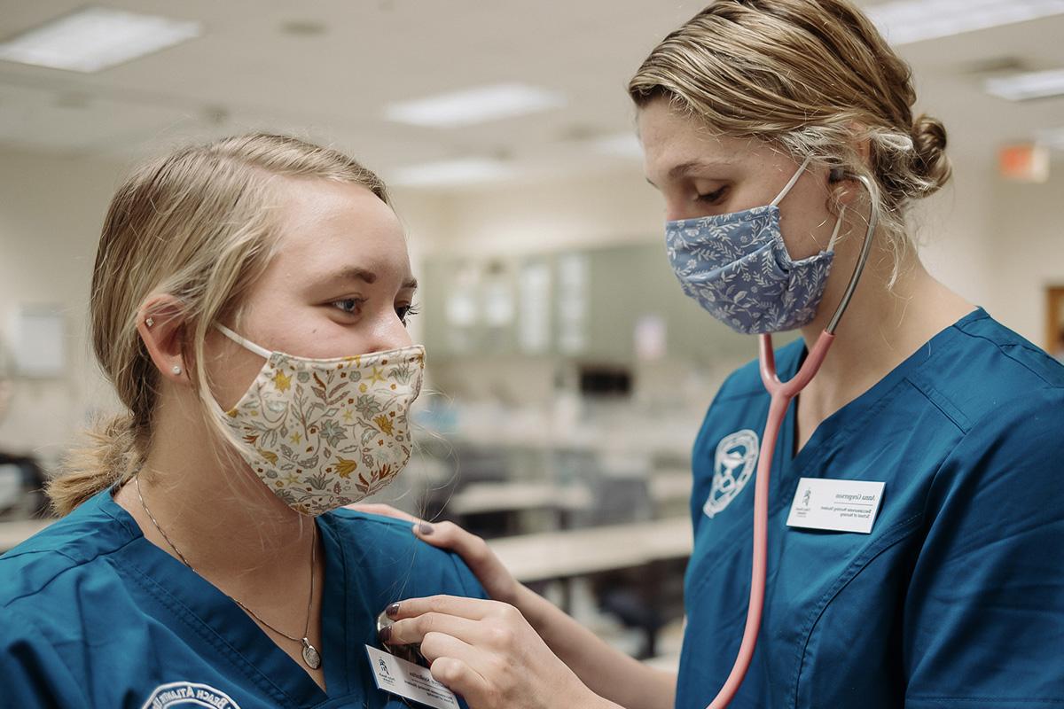 a nursing student listening to the heartbeat of a不her student through a stethoscope